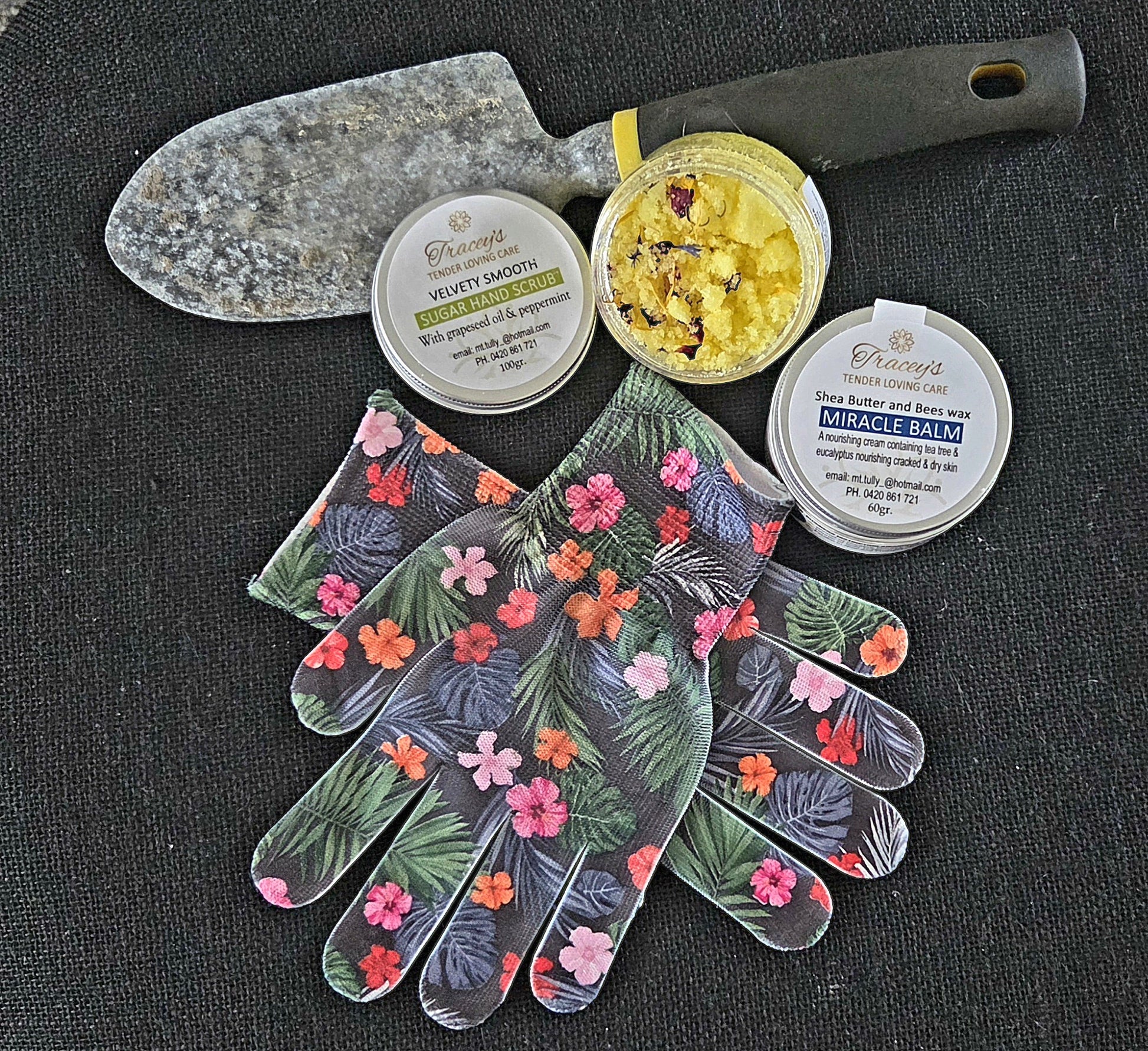 Gardening tools and gloves with branded products on a dark surface